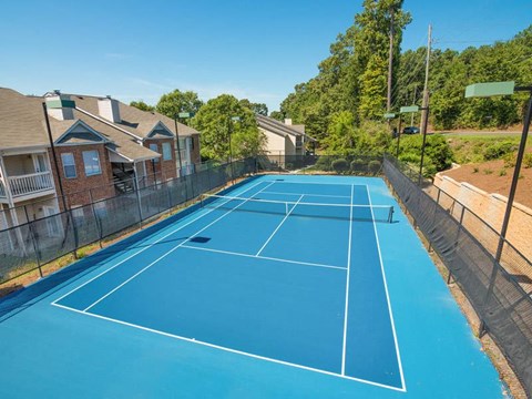 Outdoor lighted full tennis court with high black fencing at Chace Lake Villas apartments in Birmingham, AL